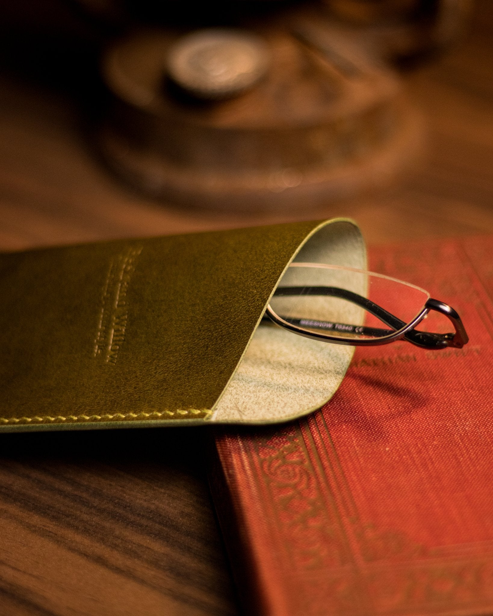 close up photo of glasses peaking out of a leather glasses case in olive