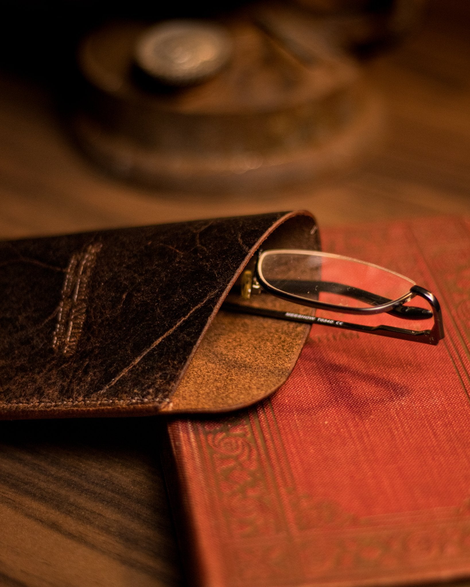 Photo of glasses peaking out of a brown leather glasses case
