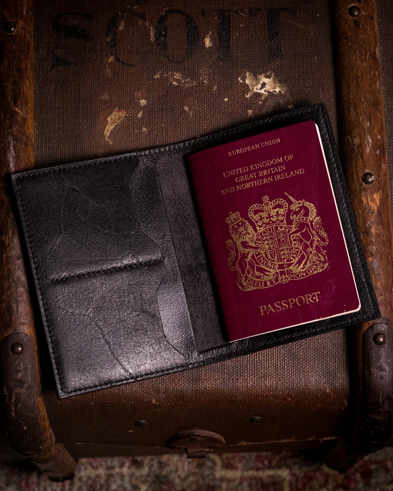 british passport in a black leather cover on a wooden trunk