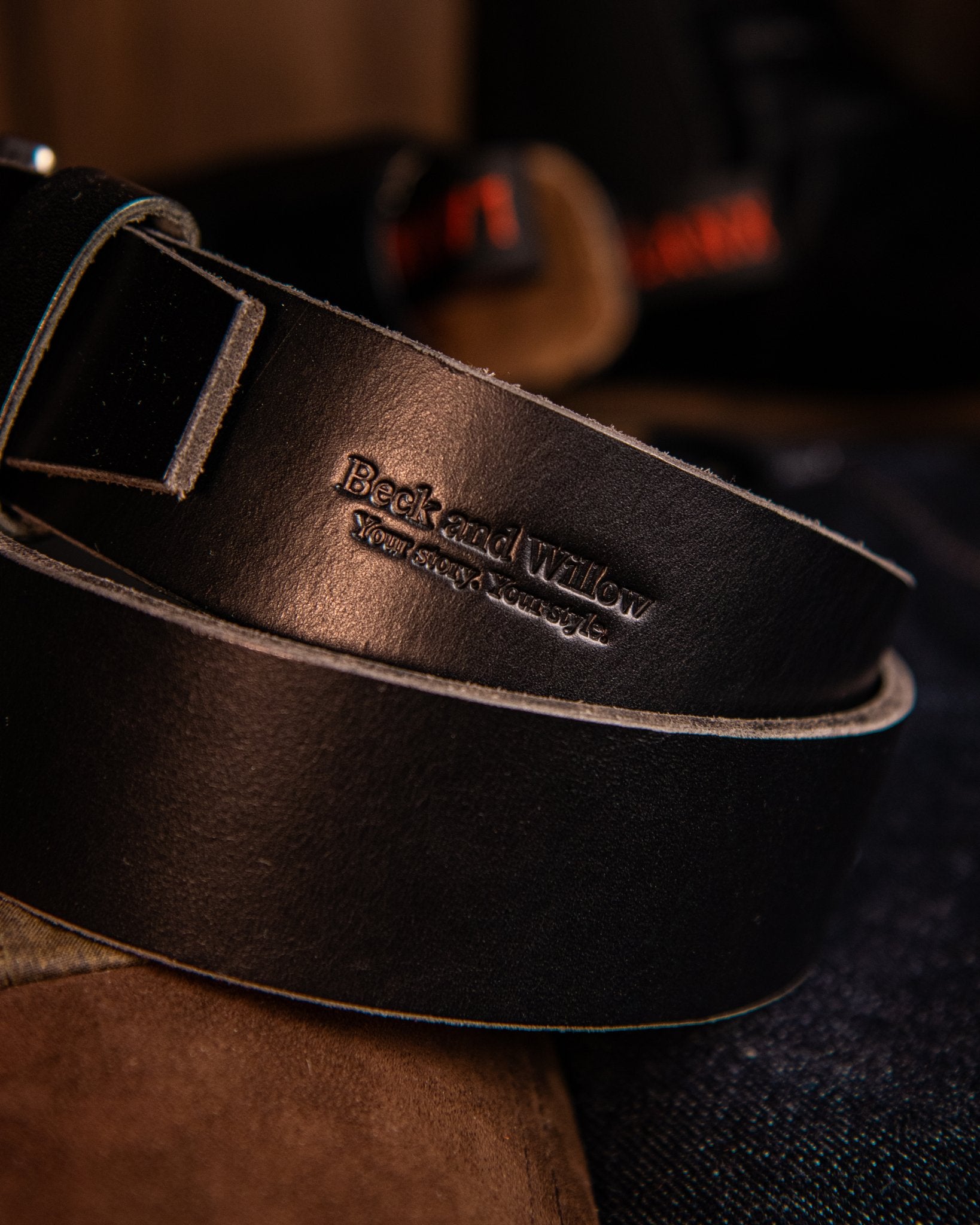 Black leather belt with visible branding on a dark background