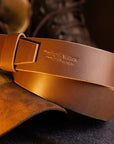 Brown leather belt with 'Beck and Willow' branding on a dark background