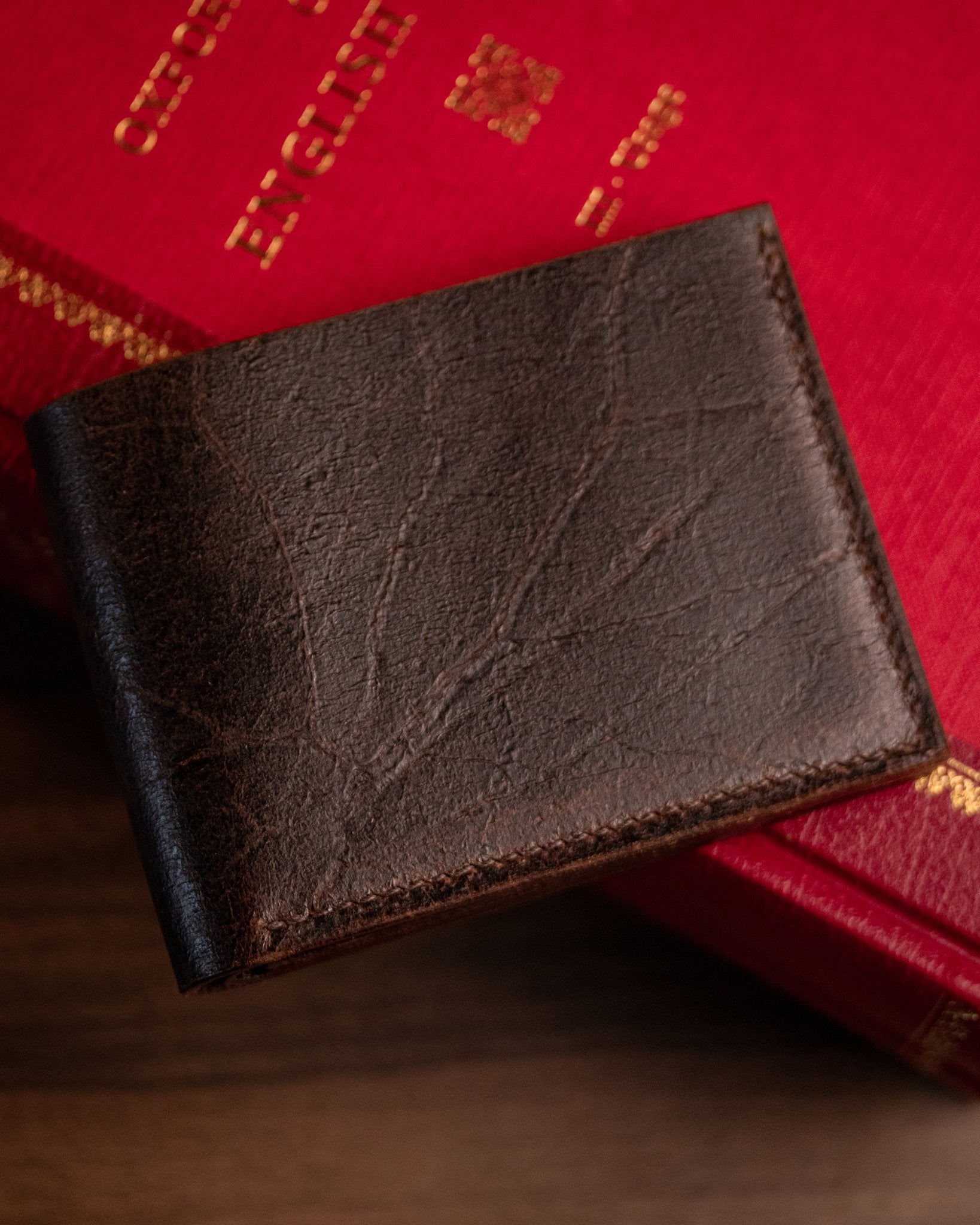closed brown wallet sat on an oxford book