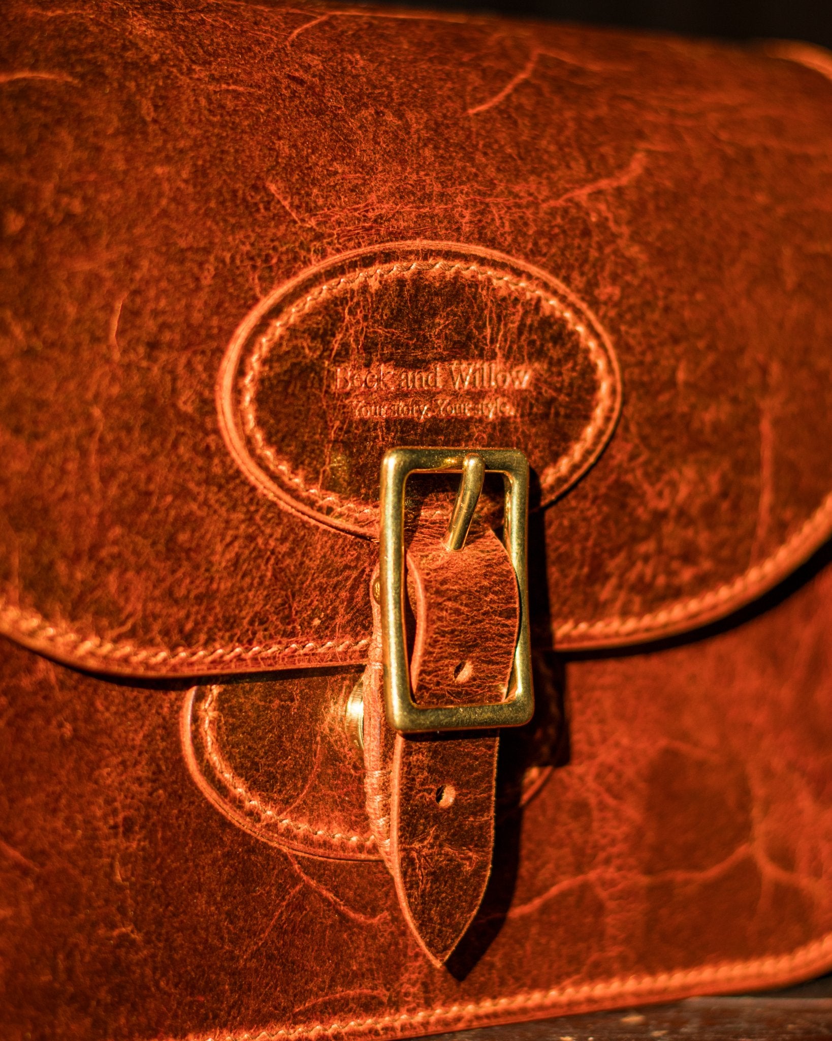 close up picture of the strap closure on a leather handbag covering the magnet below