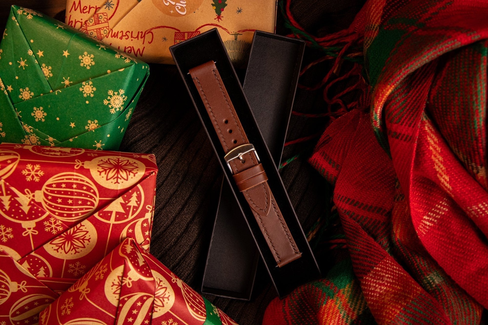 hero image of a brown leather watchstrap in a black box surrounded by christmas presents