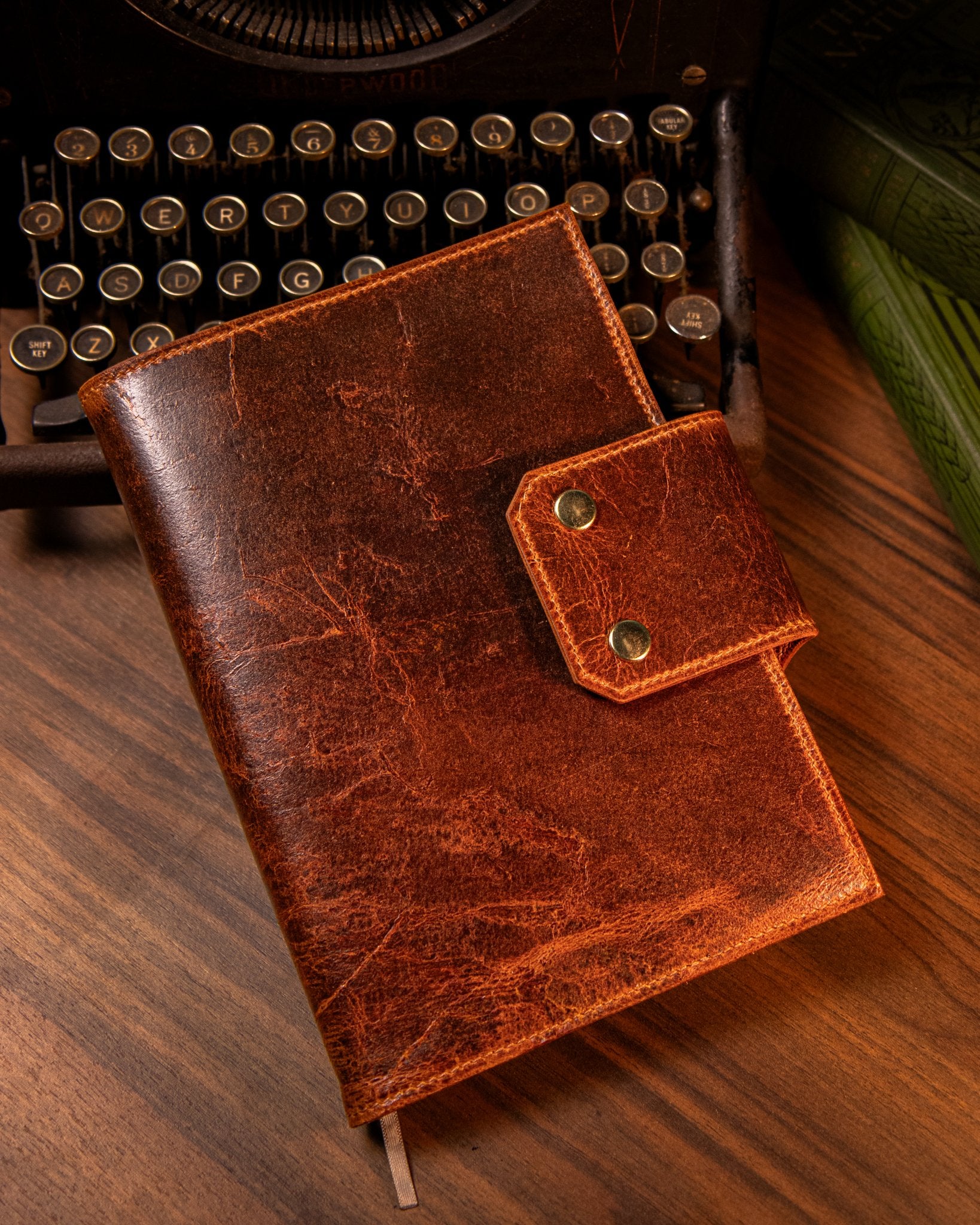 Tan leather notebook on a wooden surface with an old typewriter in the background