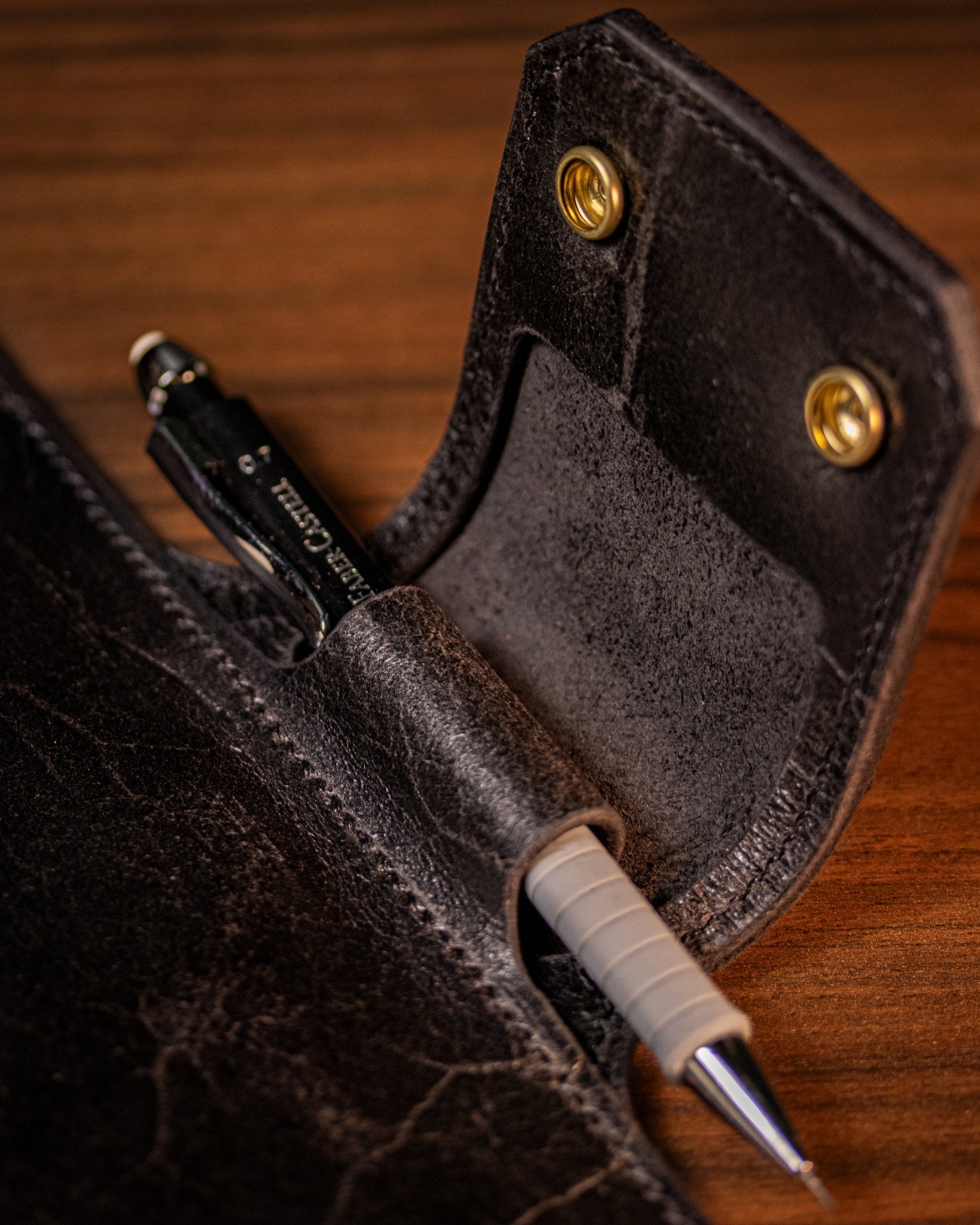 Close-up of a leather notebooks pen holder on a wooden surface