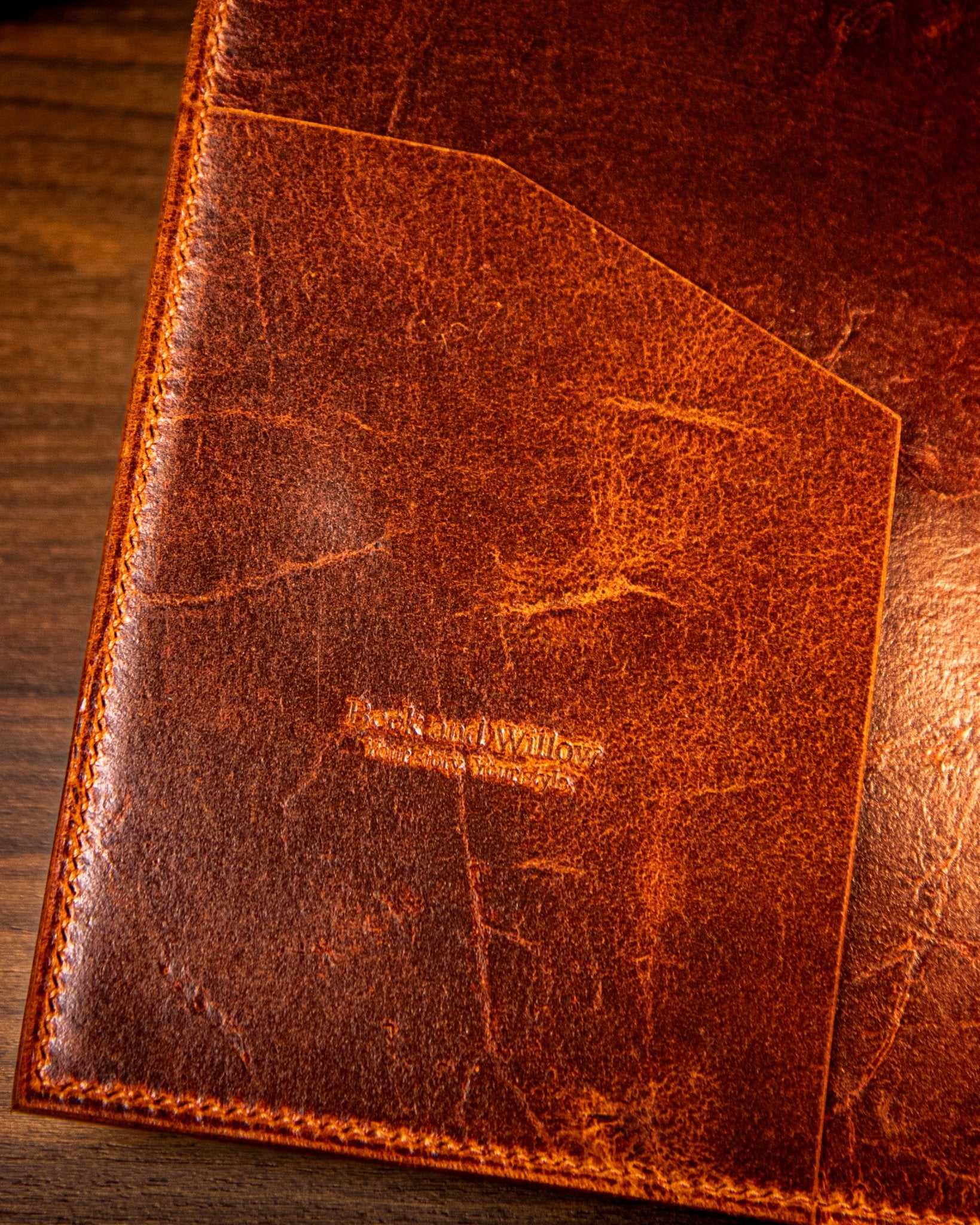 Tan leather pocket with visible branding on a wooden surface
