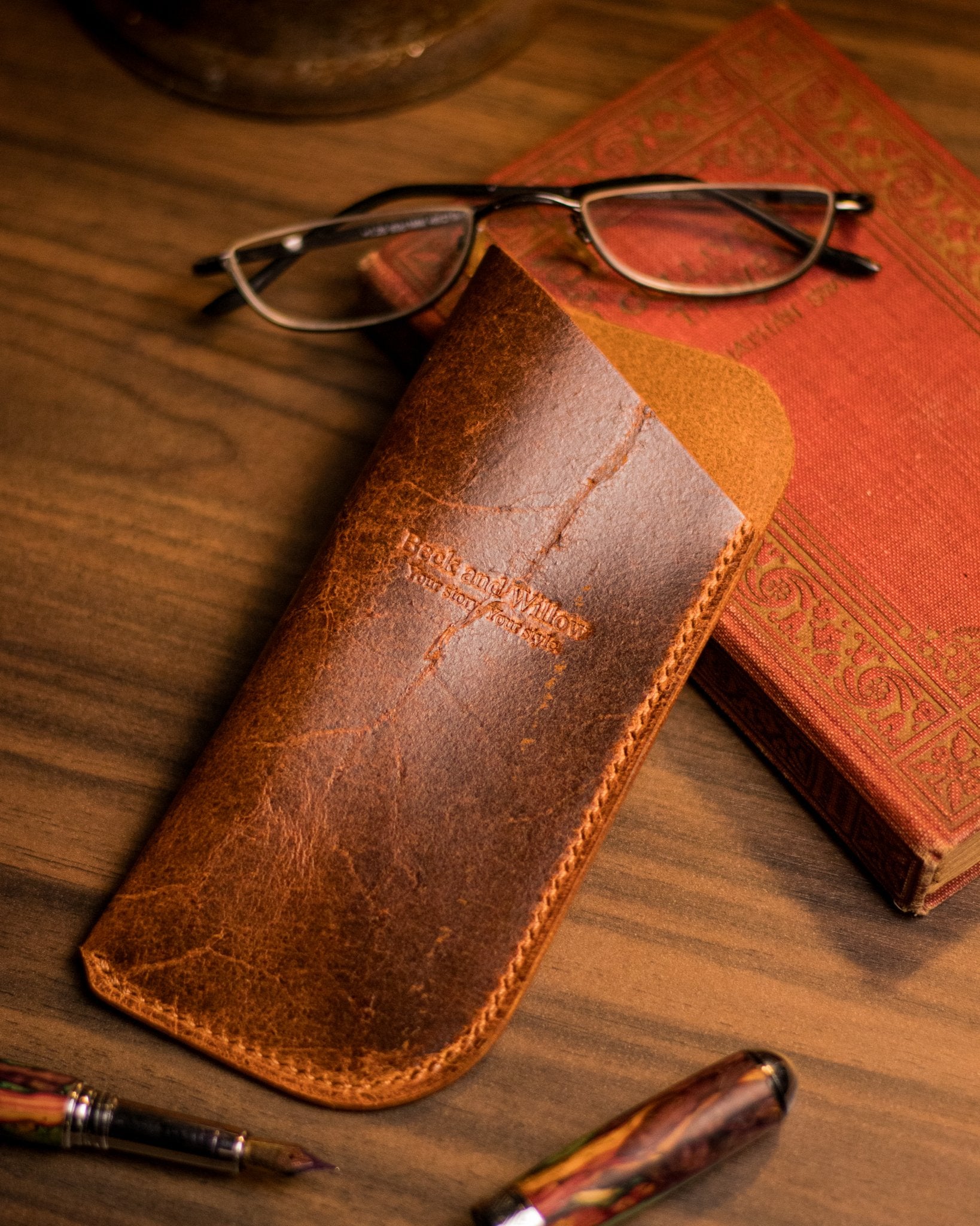Lifestyle photo of a leather glasses case with a book and glasses