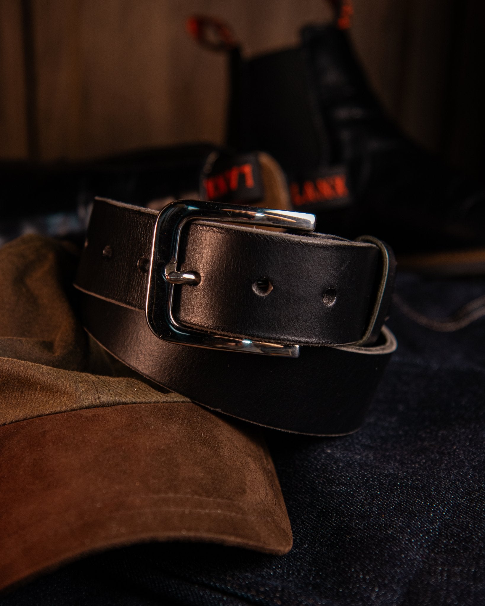 Black leather belt with silver buckle on a dark surface