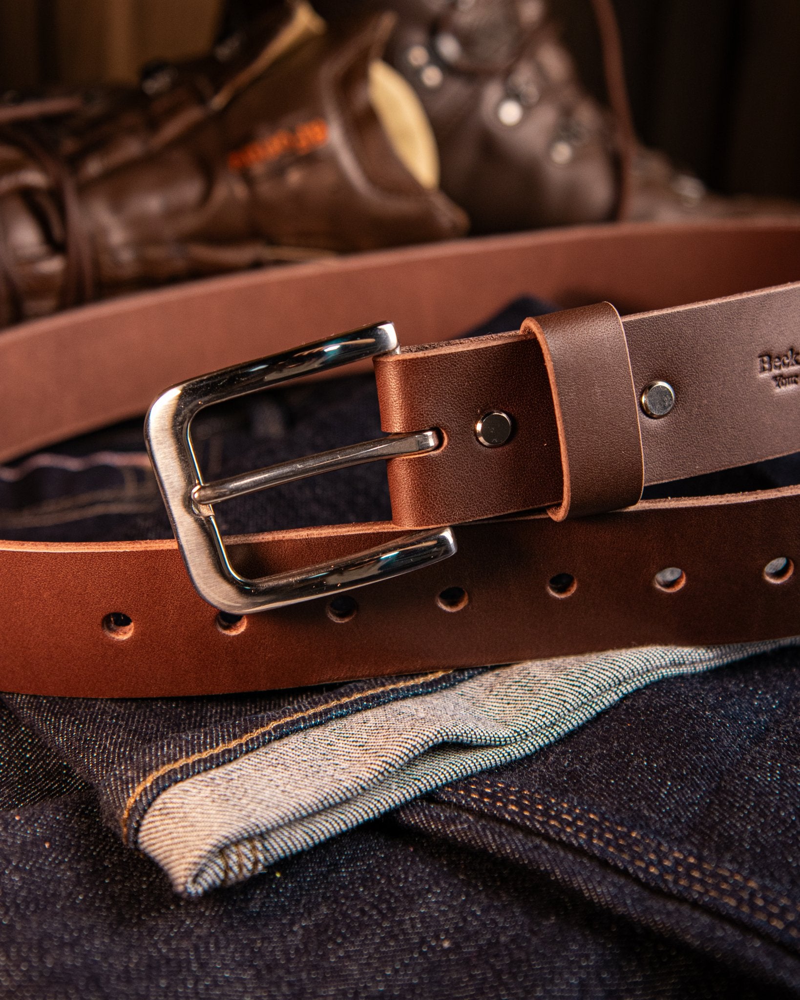 Brown leather belt with a silver buckle on a denim fabric background