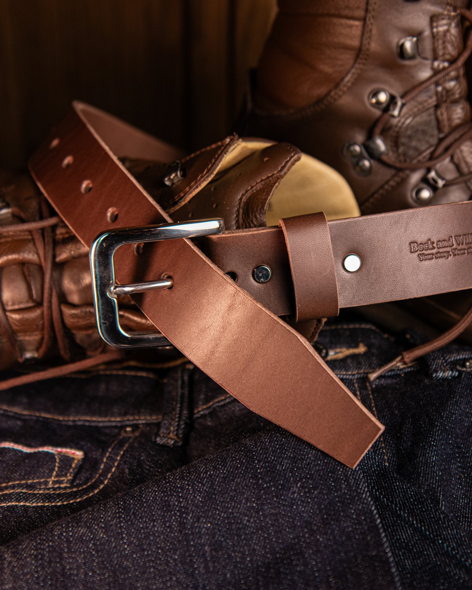 Brown leather belt with silver buckle on a dark background