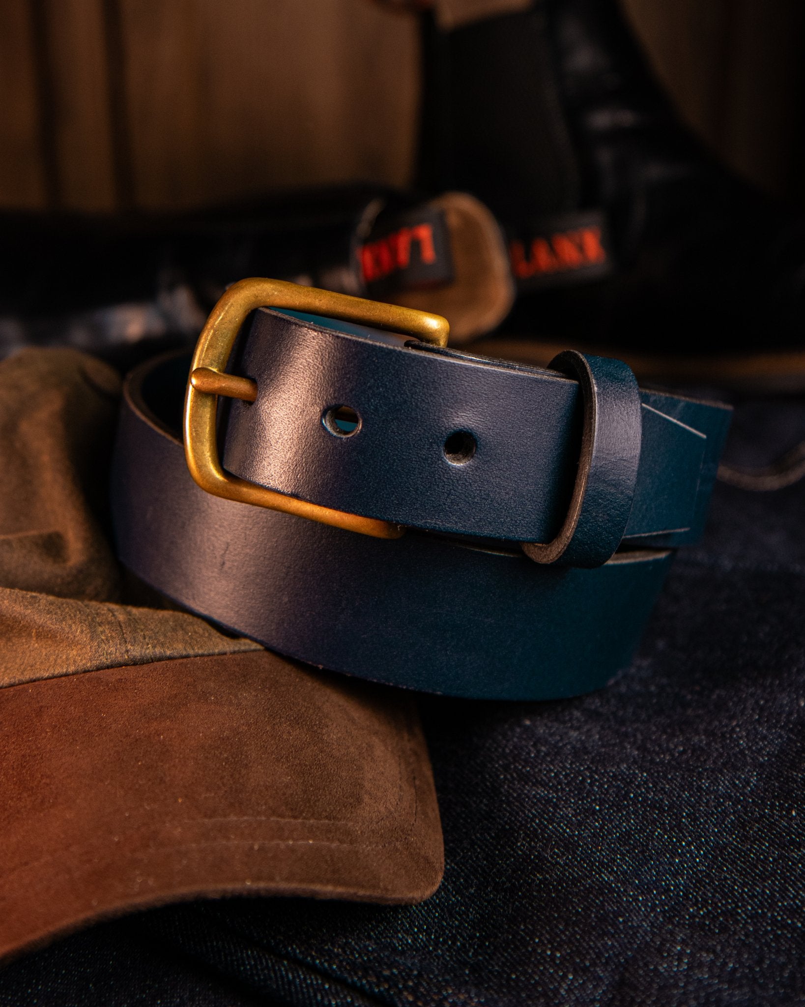 Navy leather belt with a gold buckle on a dark background