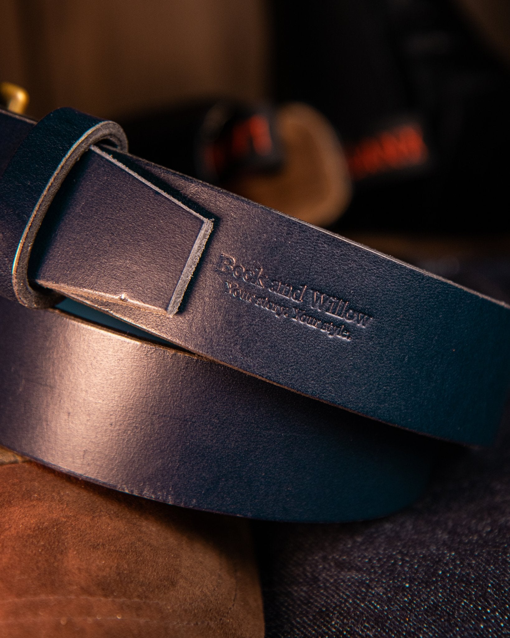 Close-up of a dark blue leather belt with a brand logo on a blurred background