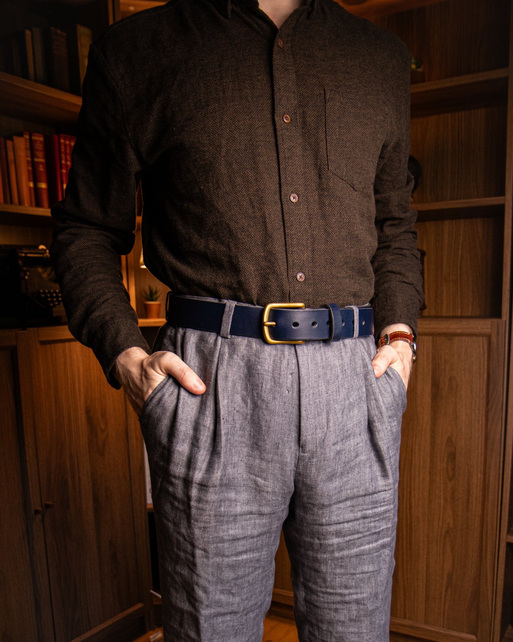 Person wearing a dark brown shirt and gray pants with a wooden bookshelf background