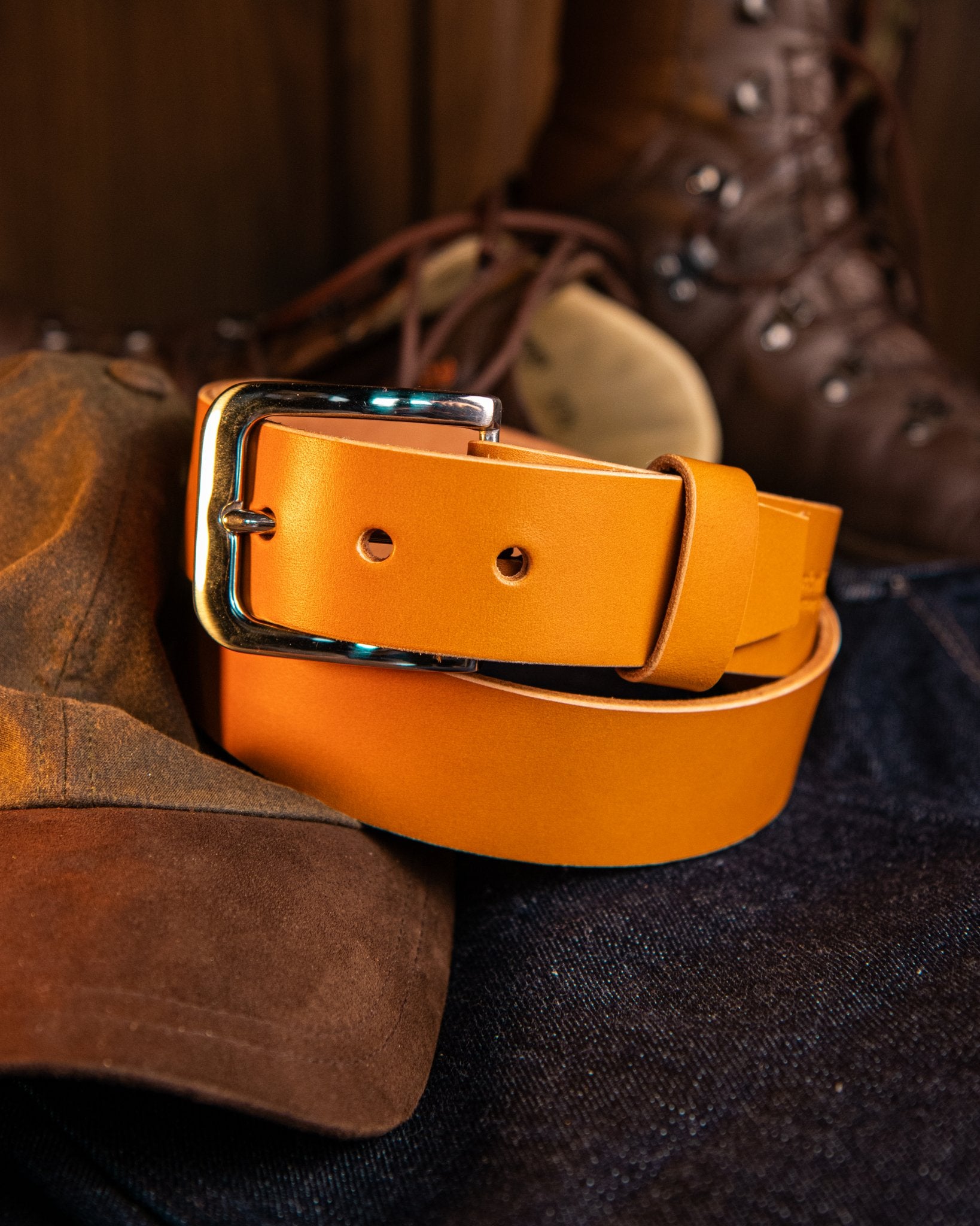 Orange leather belt with a gold buckle on a dark surface